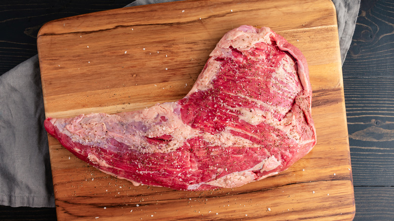 Seasoned raw tri-tip on a wooden cutting board
