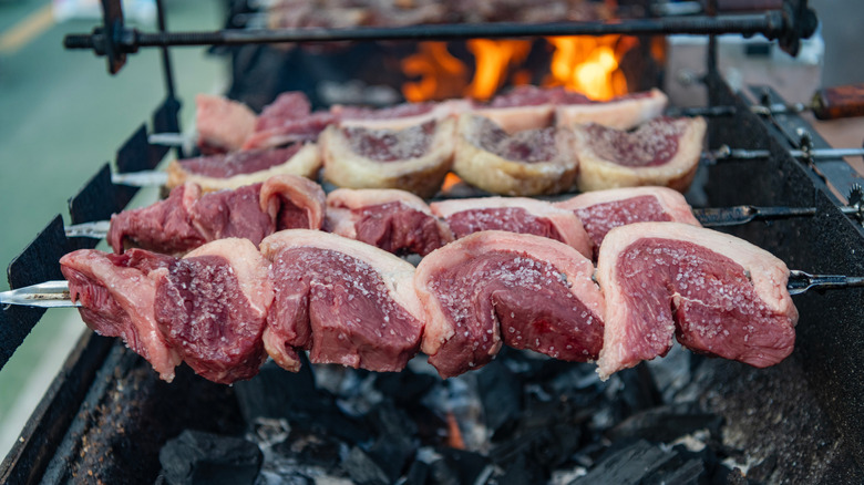 Picanha steaks coated with salt over charcoals