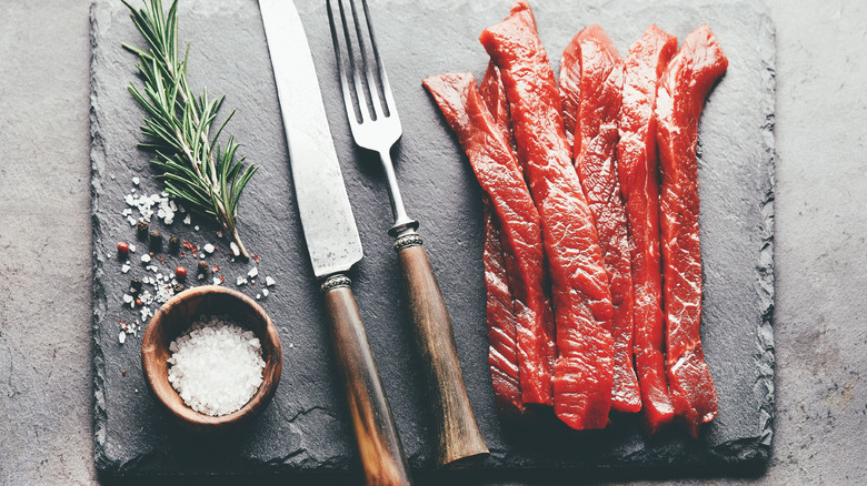 thinly cut slices of beef on black cutting board