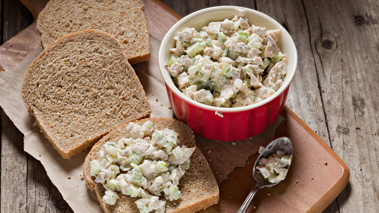 chicken salad in a bowl alongside pieces of bread
