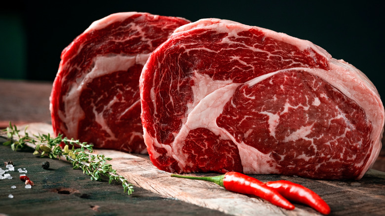 Raw ribeye steaks with herbs
