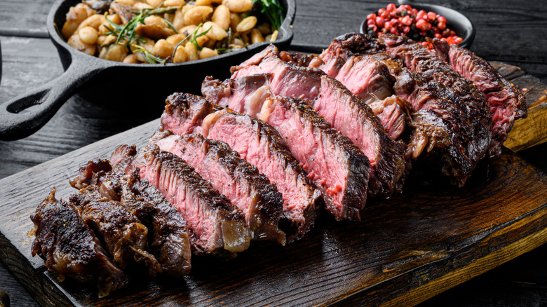 Cooked and sliced ribeye steak on cutting board