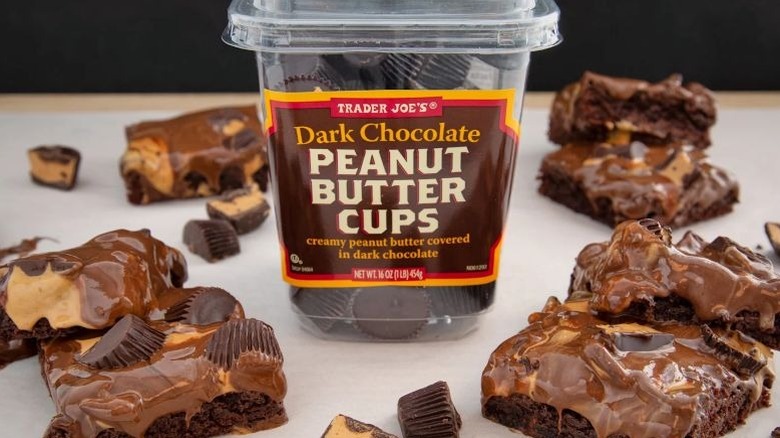 Plastic tub of Trader Joe's Dark Chocolate Peanut Butter Cups surrounded by brownies and halved cups