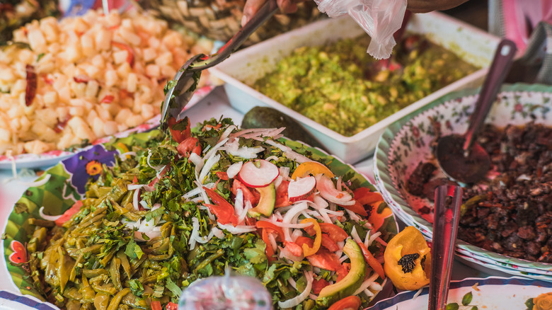 Mexican food vendor scooping nopales