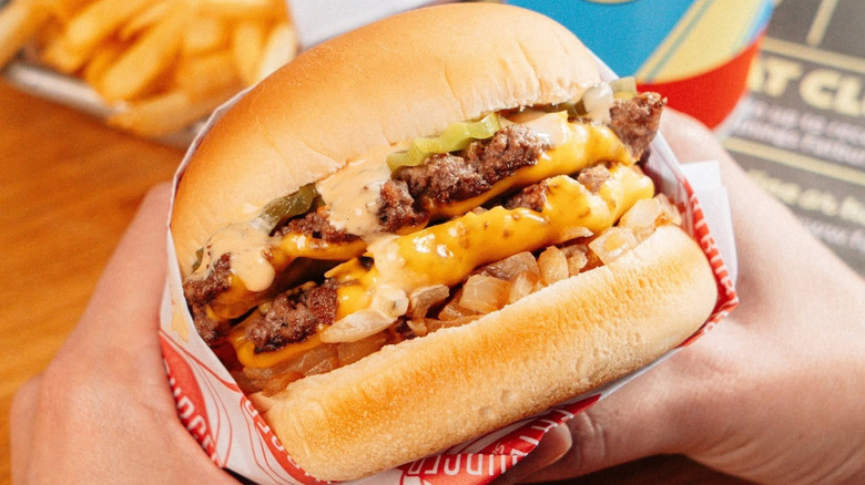 Hands hold a Fatburger Flatburger.