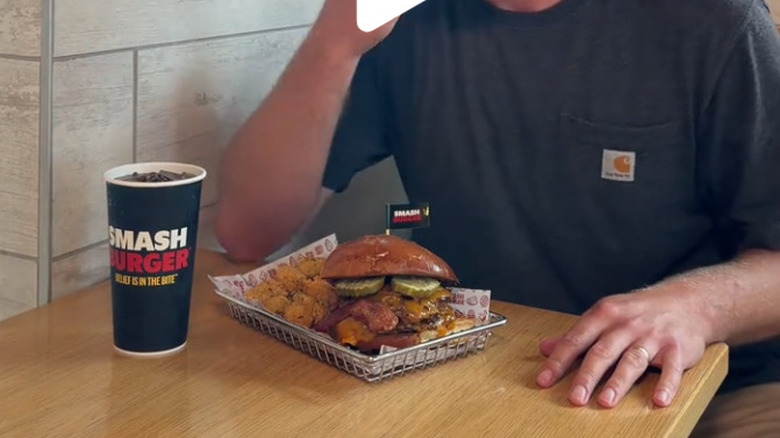 A Smashburger Pickle Stack Smash sits in a restaurant basket near french fries