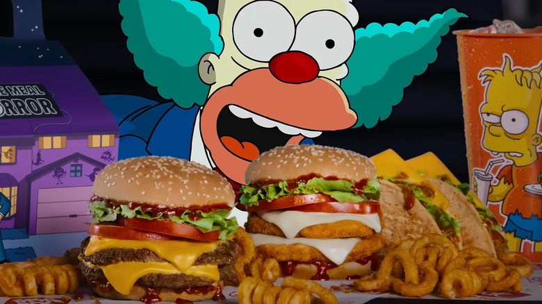 A double Krusty Burger of Terror sits on a restaurant wrapper near other food items, with animated images of Krusty the Clown and the Jack in the Box mascot in the background