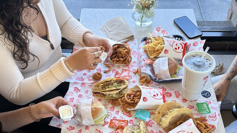 Friends sit around a table enjoying Jack in the Box food
