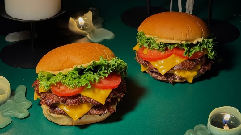 Two burgers from Shake Shack sit on a green surface