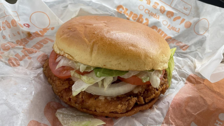A crispy chicken sandwich sits on a wrapper