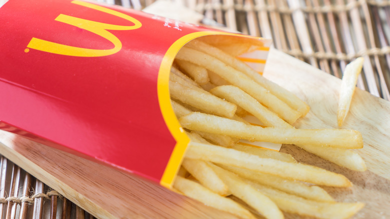 A container of McDonald's french fries tipped on its side on a wooden serving vessel