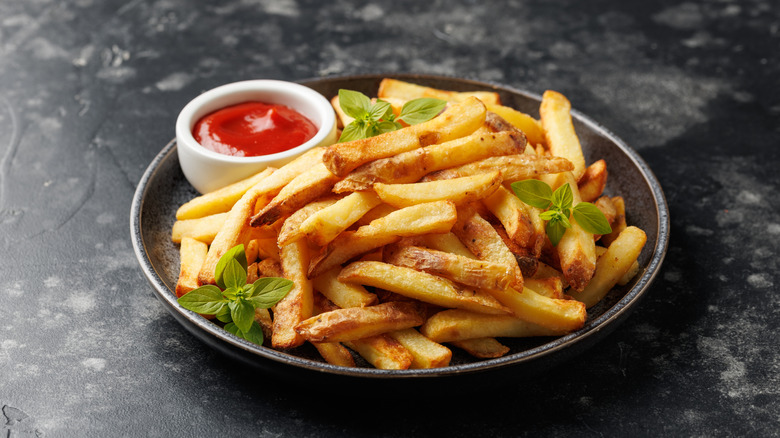 A plate of golden brown french fries with ketchup