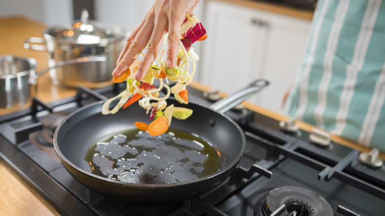 tossing veggies into pan with oil