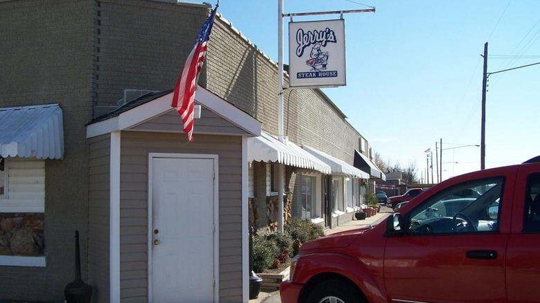 The exterior of Jerry's, simple brown brick, an American flag above the door, a red truck to the