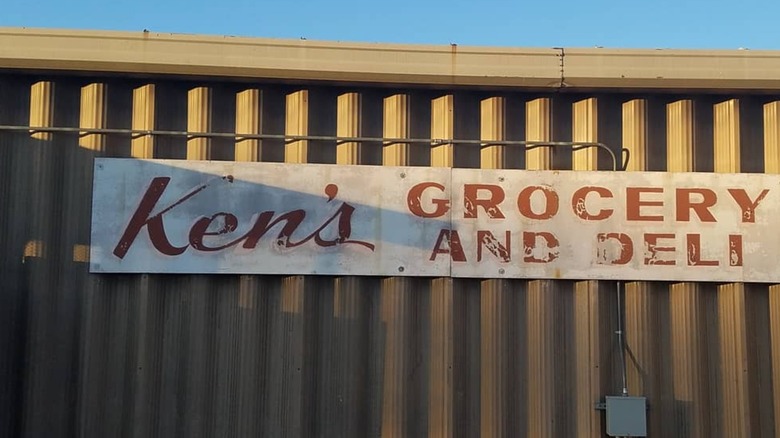 An old metal wall with an old sign saying Ken's Grocery and Deli