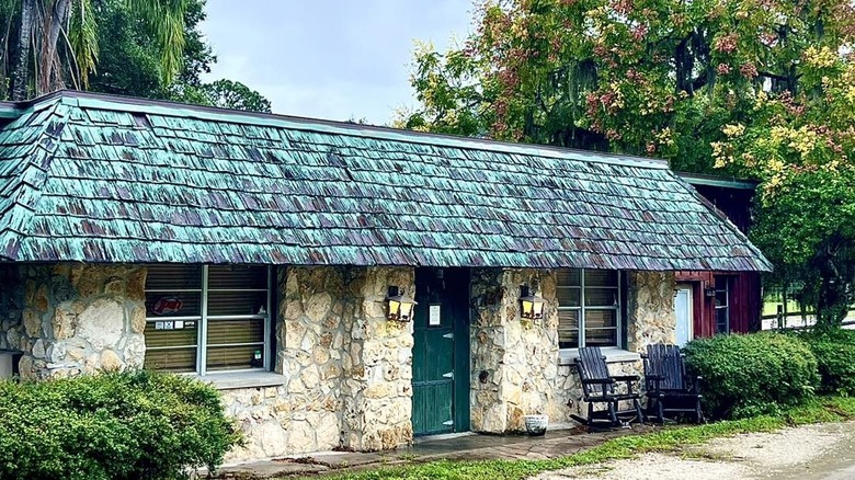 A small light yellow brick building with a turquoise shingle roof