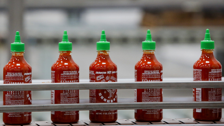 bottles of sriracha on conveyor belt