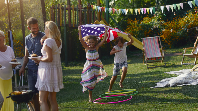 A family enjoying a Labor Day backyard barbecue and kids waving an American flag on