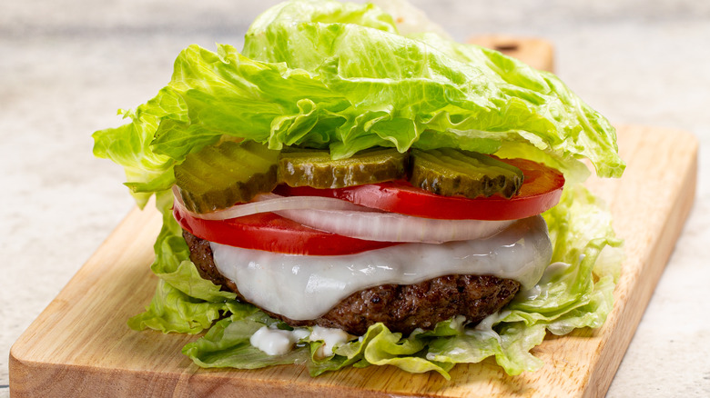burger and toppings sandwiched by lettuce leaves
