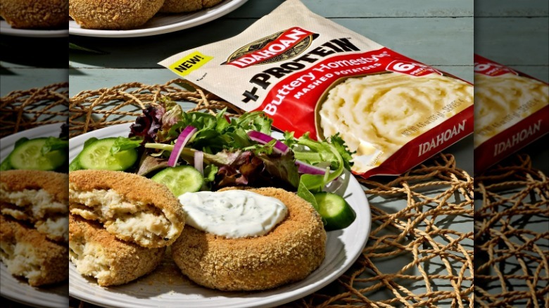 A plate of fish cakes and salad sit next to a bag of protein-enhanced Idahoan mashed potatoes