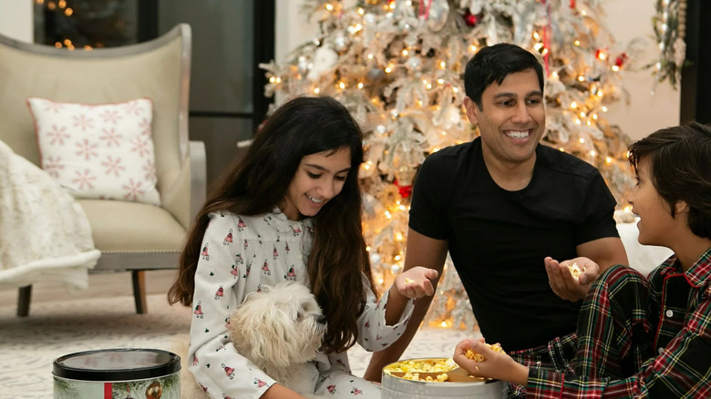 A family enjoys popcorn from a festive tin