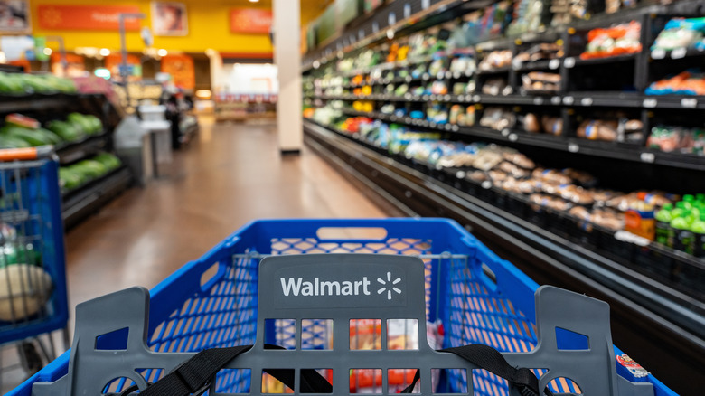 A shopper's view looking over the top of a Walmart shopping cart, with the store blurred in the background