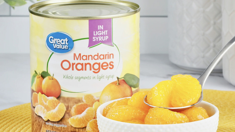 A can of Great Value Mandarin Oranges next to a bowl of the fruit.