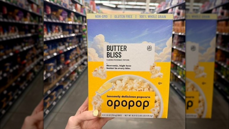 A hand holds a box of Opopop Microwave Popcorn in the Butter Bliss flavor