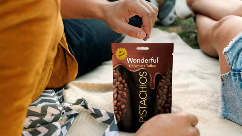 A hand reaches into a bag of Wonderful Chocolate Toffee Pistachios