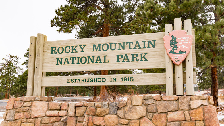 Wooden Rocky Mountain National Park sign surrounded by evergreen trees