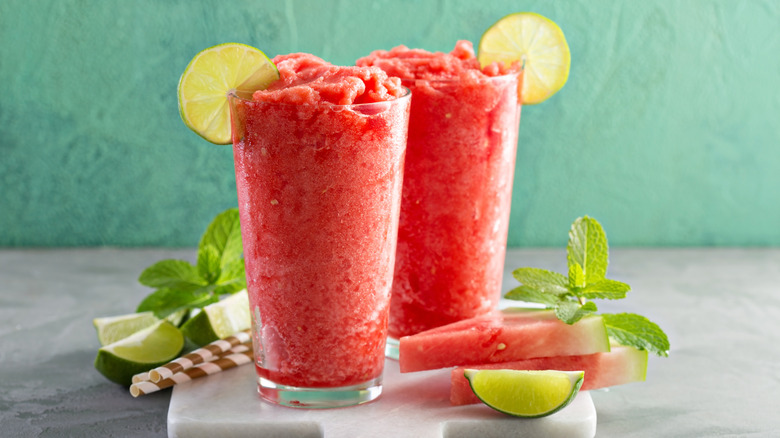 Frozen watermelon slushies in tall glasses with lime garnish