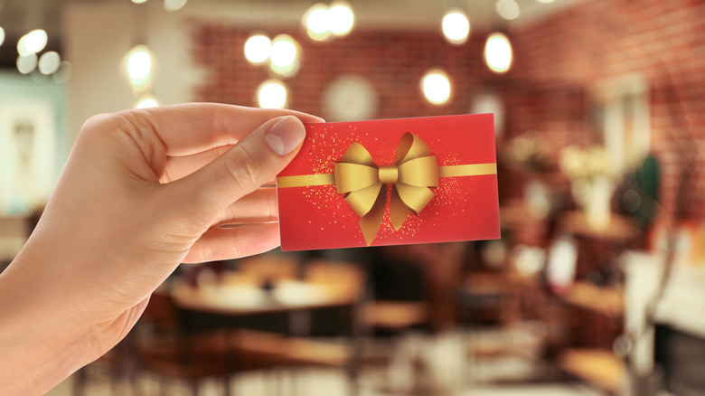 Woman holding gift card in restaurant