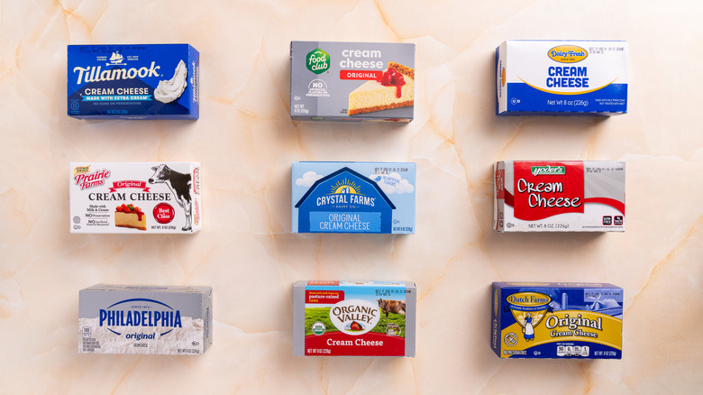 Several brands of cream cheese arranged on a marble surface.