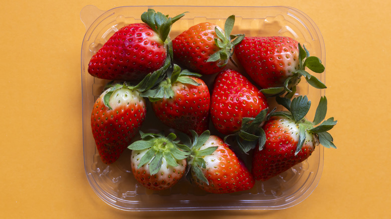 Ripe, fresh strawberries sit in a plastic container