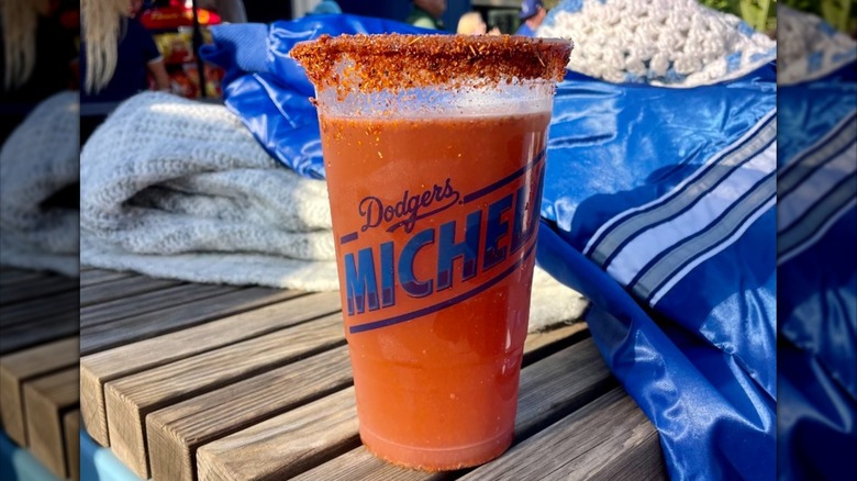 Spice and salted rim of a cup on a picnic table filled with michelada
