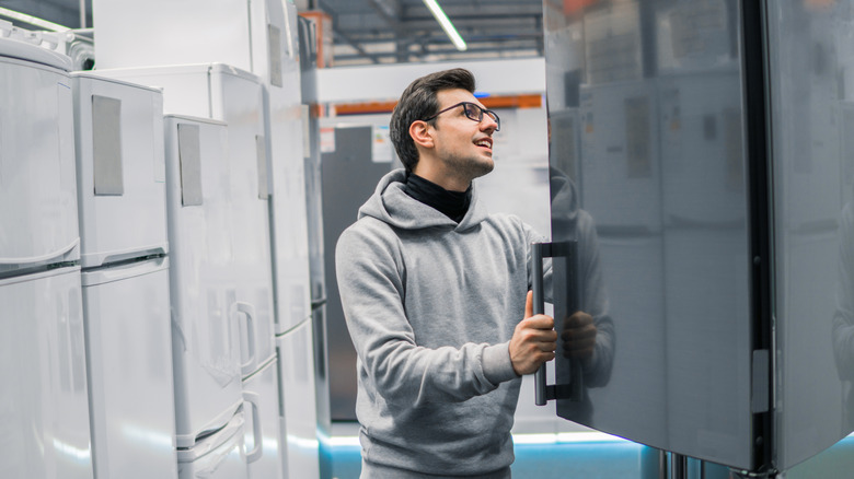 A homeowner examines a floor model refrigerator.