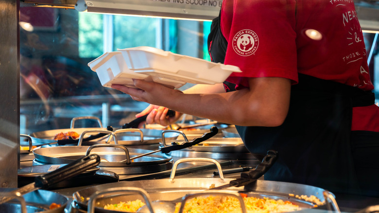 An employee serves up dishes from the food line at a Panda Express