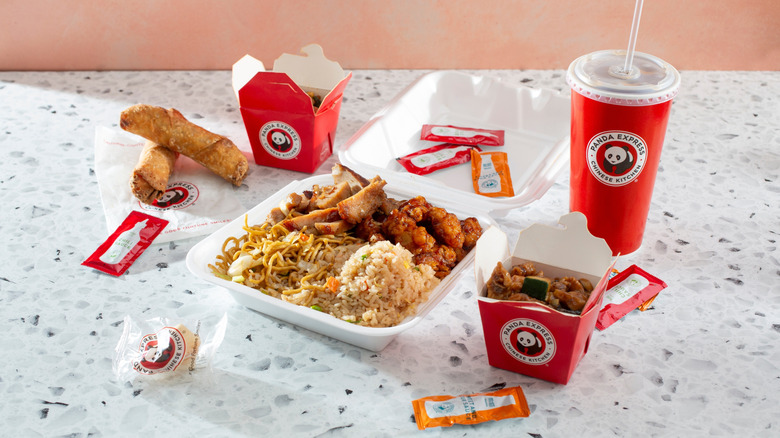 A Panda Express meal with a side of egg rolls and a fortune cookie.
