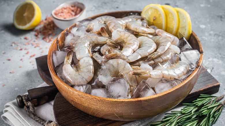 Raw shrimp in a bowl with ice and lemon wheels