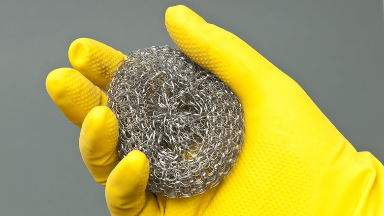 gloved hand holding steel wool