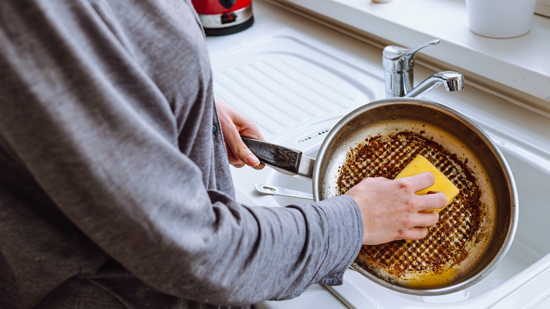 Person washing a burnt pan