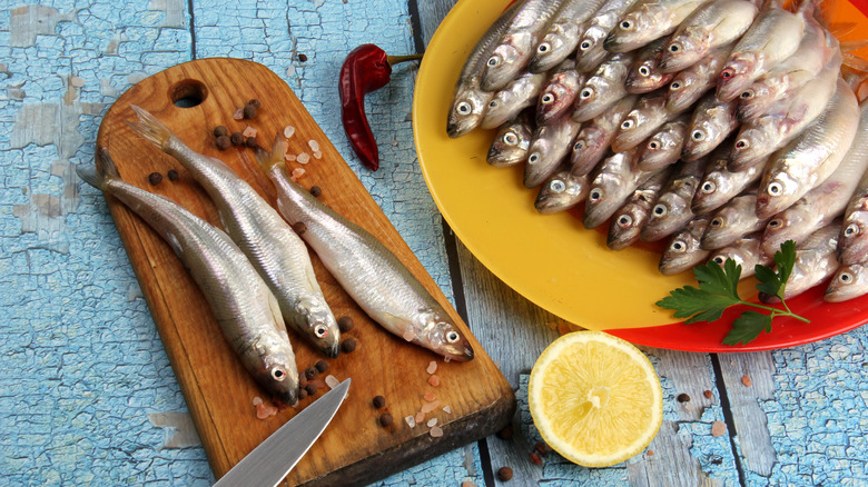 whole raw smelt on a cutting board and plate