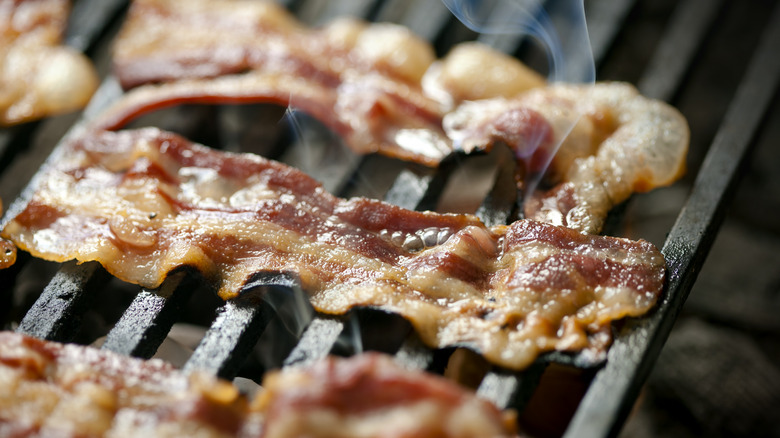Strips of bacon being cooked on a grill