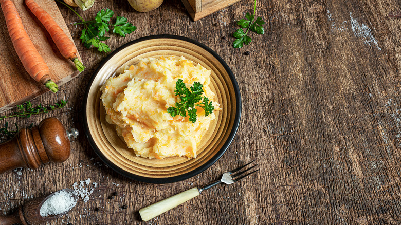 A bowl of mashed parsnips sits on a wooden surface