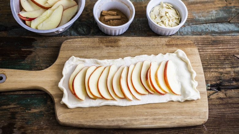 Apple slices and pie dough on cutting board