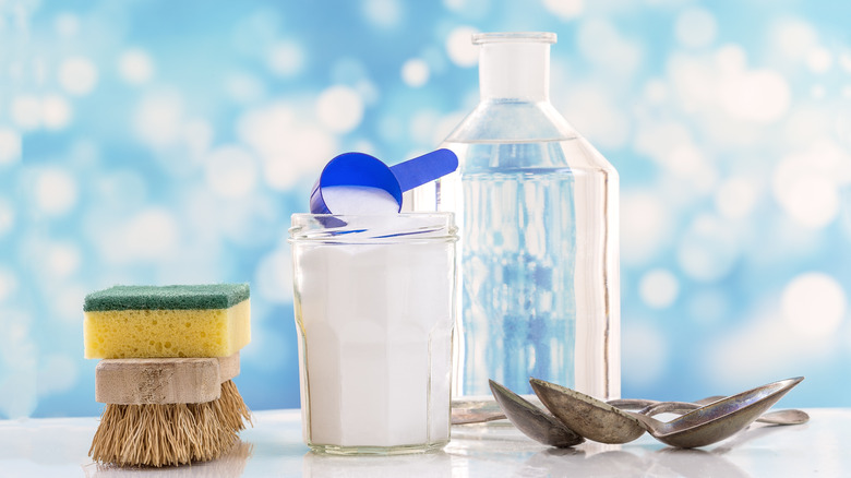 Jar of baking soda with brushes and rusty spoons