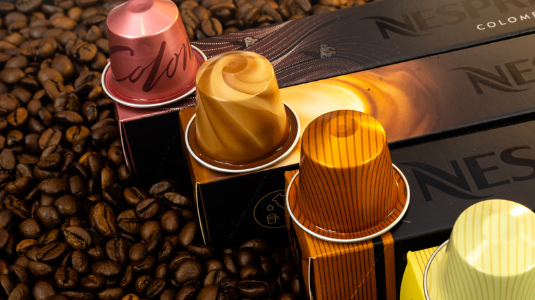 Nespresso pods on their respective boxes, surrounded by coffee beans