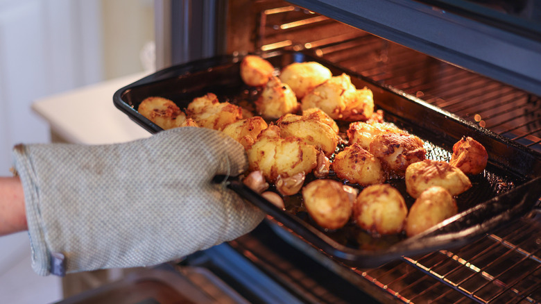 Removing baked potatoes from an oven.
