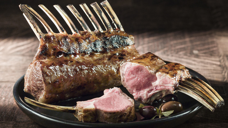 A rack of lamb on a plate with olives