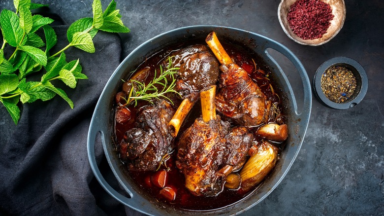 Braised lamb shanks next to herbs and seasonings